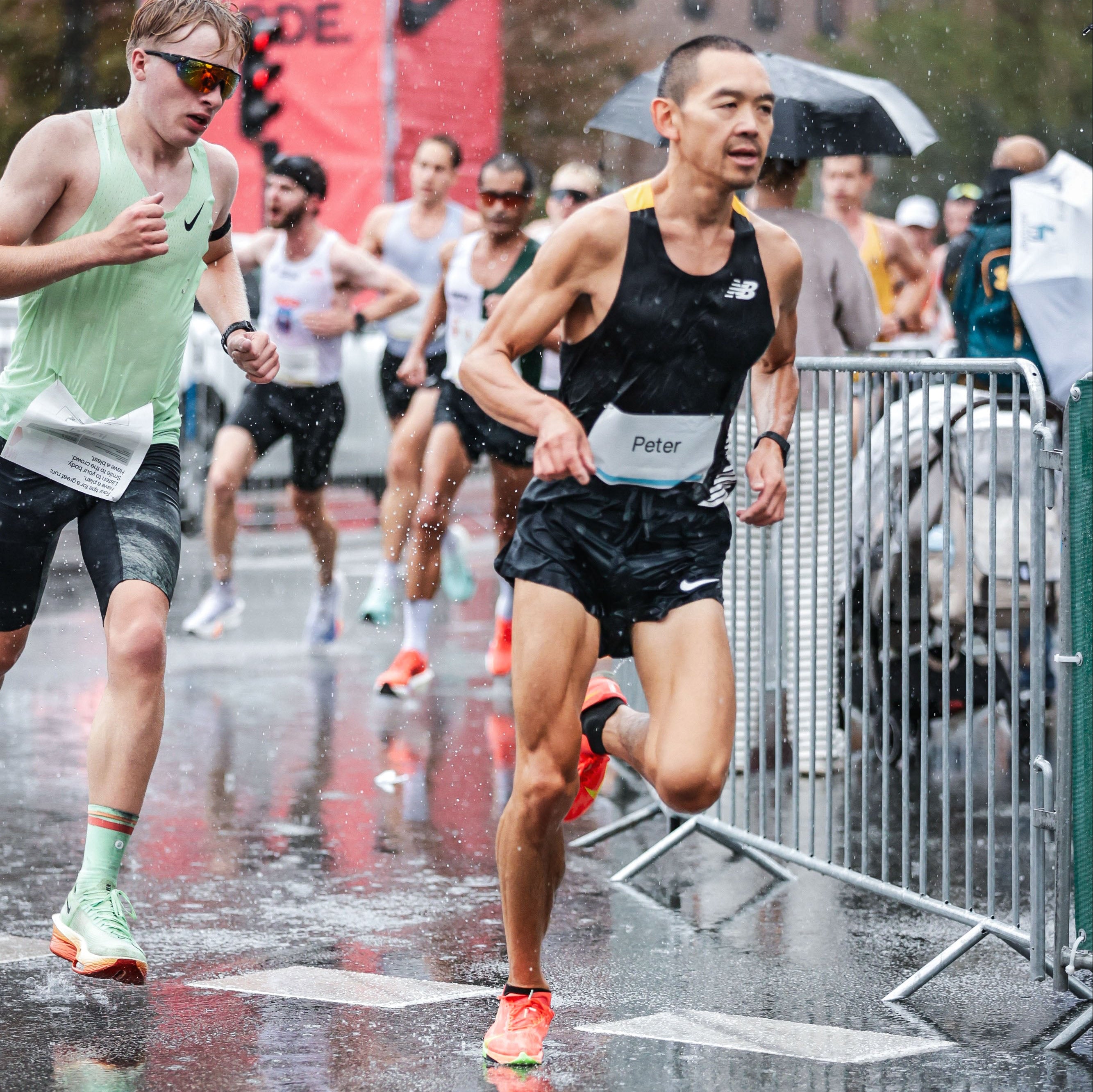 Runners participating in a race on a wet street with a Nike advertisement in the background.